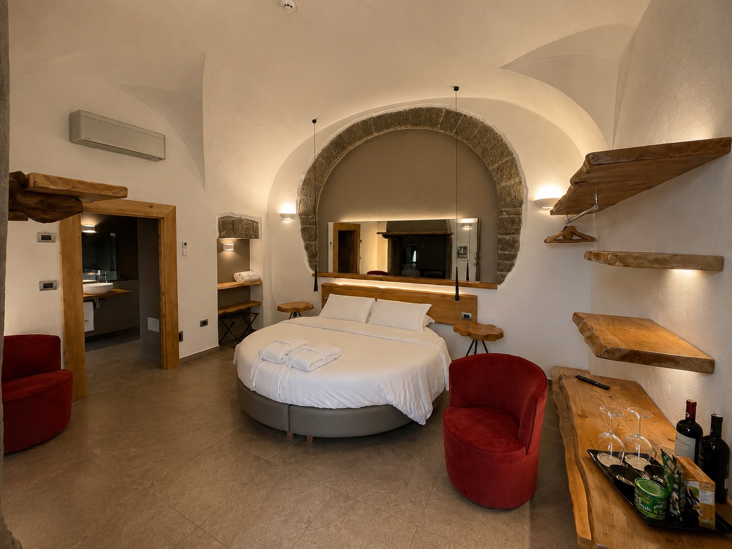 Camera della suite con ingresso autonomo, letto rotondo e arco in pietra